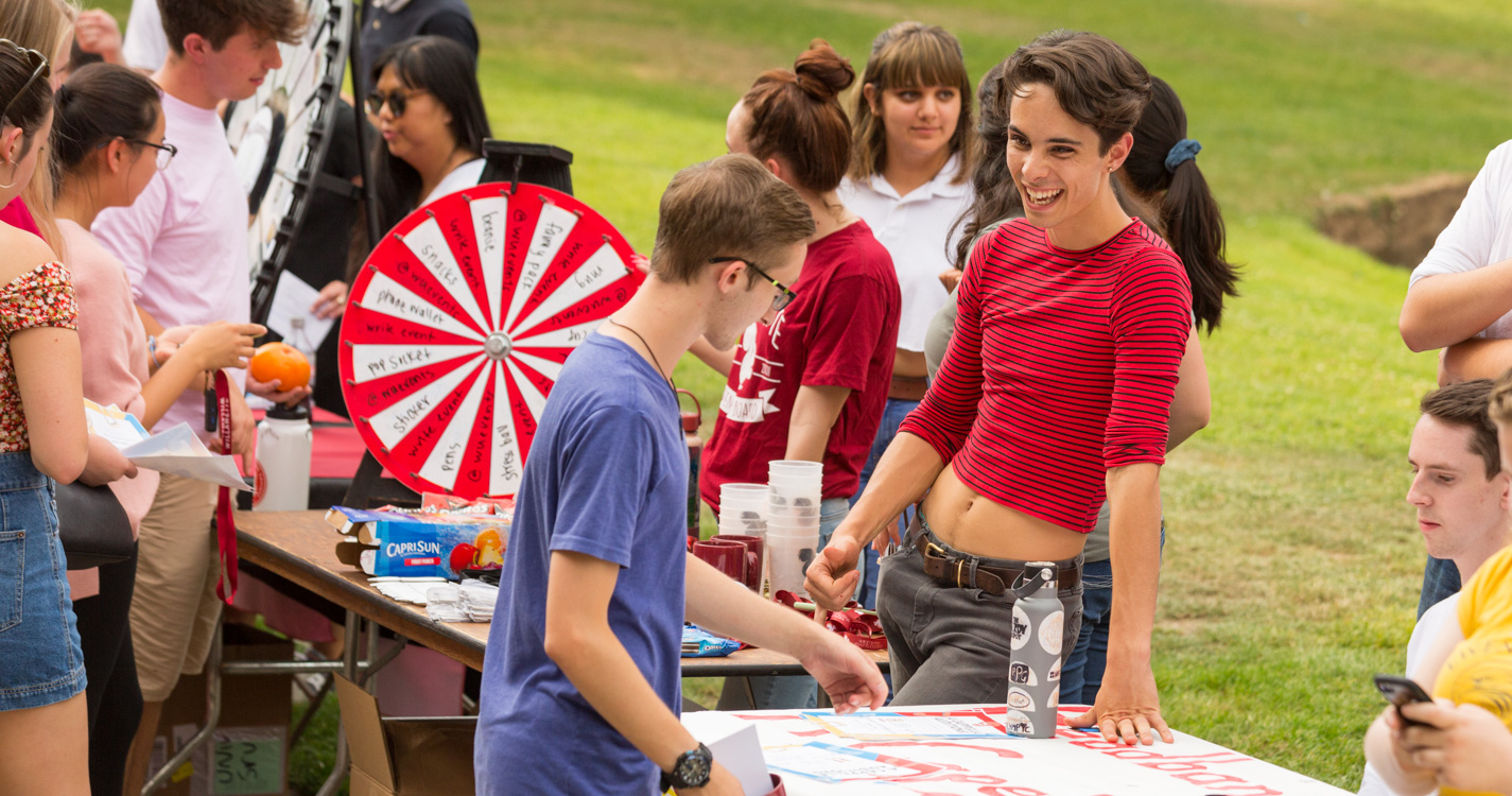 Two students converse at a table decorated with painted poster board