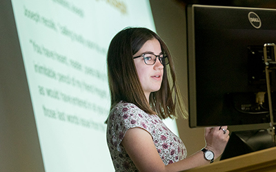 A student teaches before a projection screen