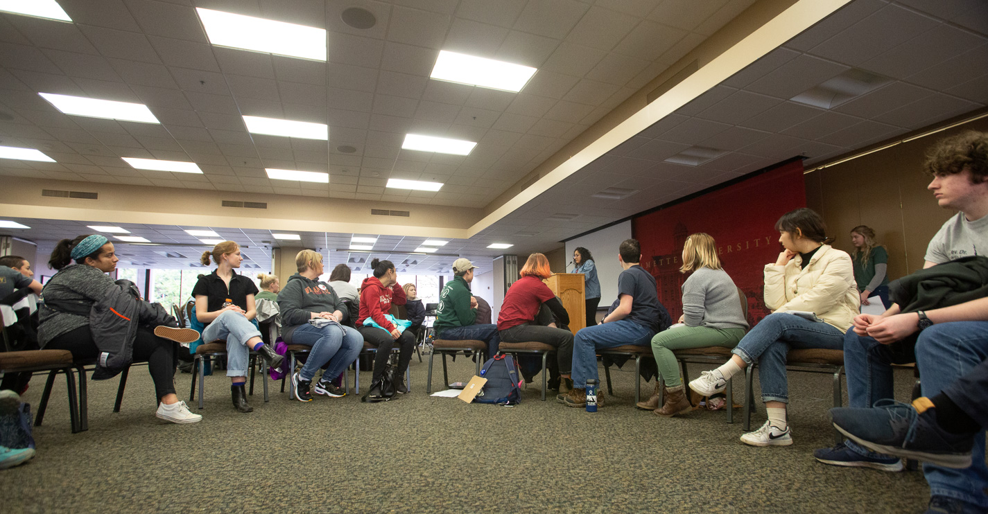 Students, employees and alumni gathered in Cat Cavern sit in circles