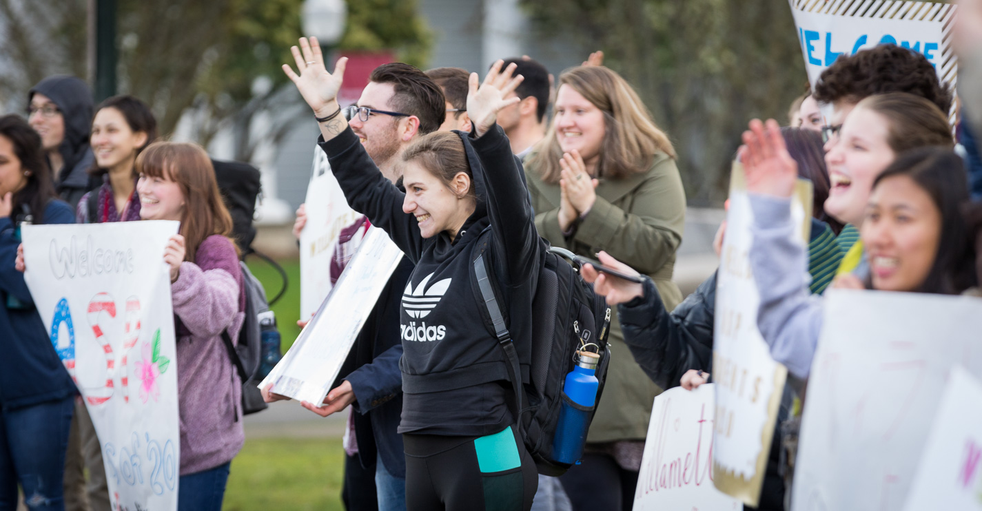 An excited Bearcat waves their hands in the air as the new students disembark the bus