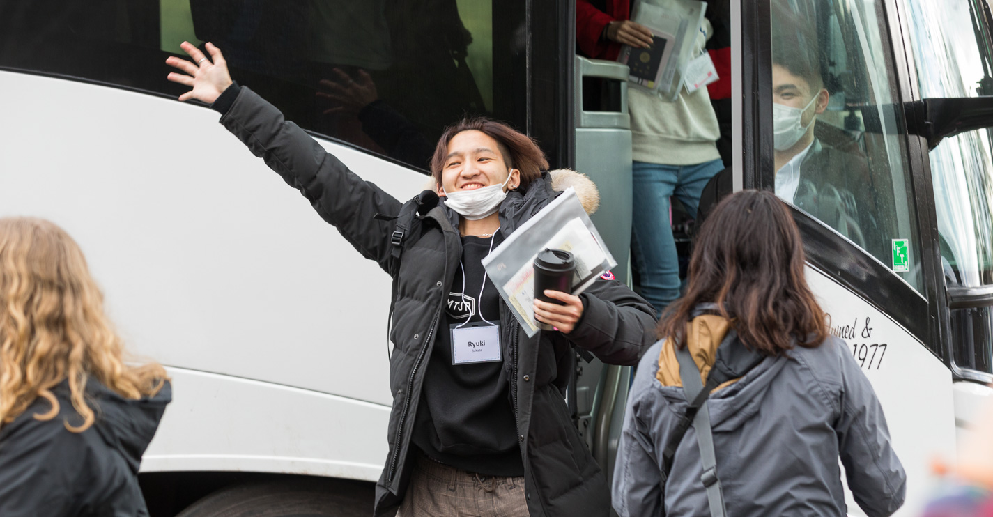 An ASP student with outstretched arms runs from the bus to greet a friend.