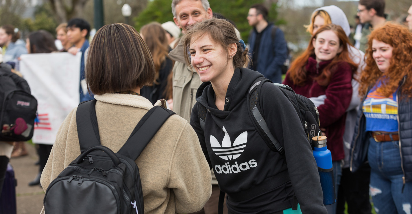 As a student walks from the bus, another steps forward from the crowd extending a handshake