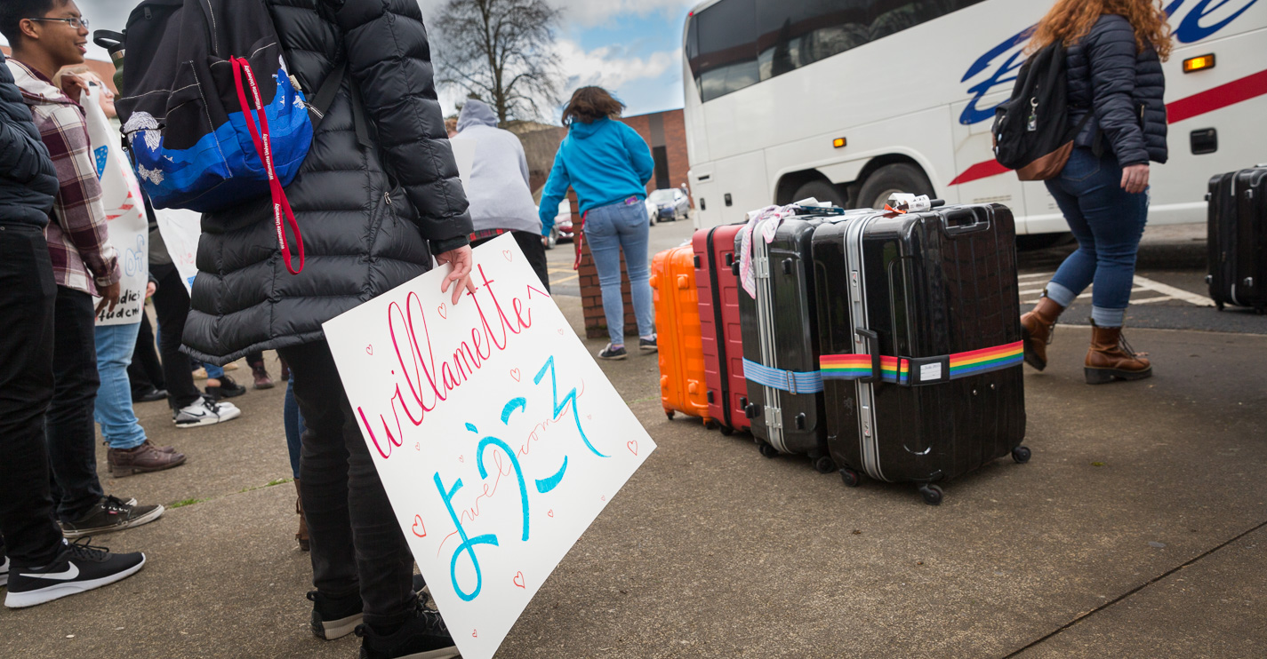 Suitcases line the parking lot curb near a sign that says Willamette in English and Japanese