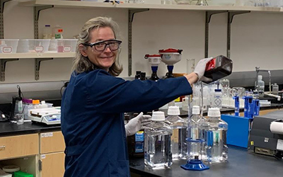 Professor Kirk pours solution into a beaker