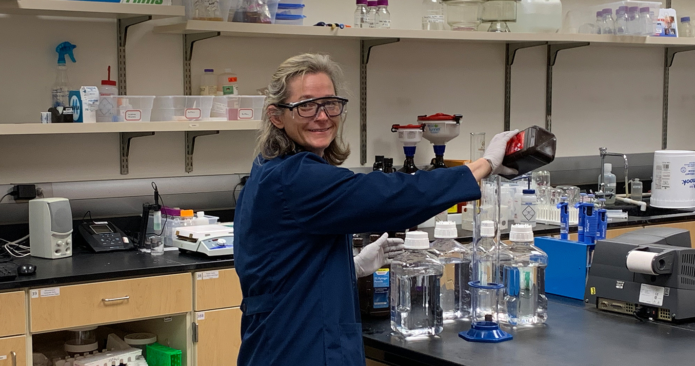 Professor Kirk pours solution into a beaker