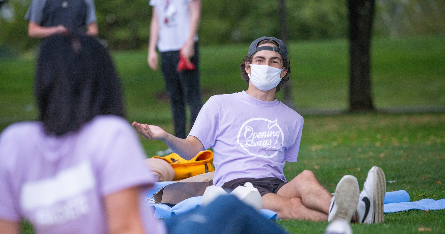 Two students talking on laying on grass on the Quad