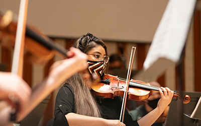 masked student plays violin 