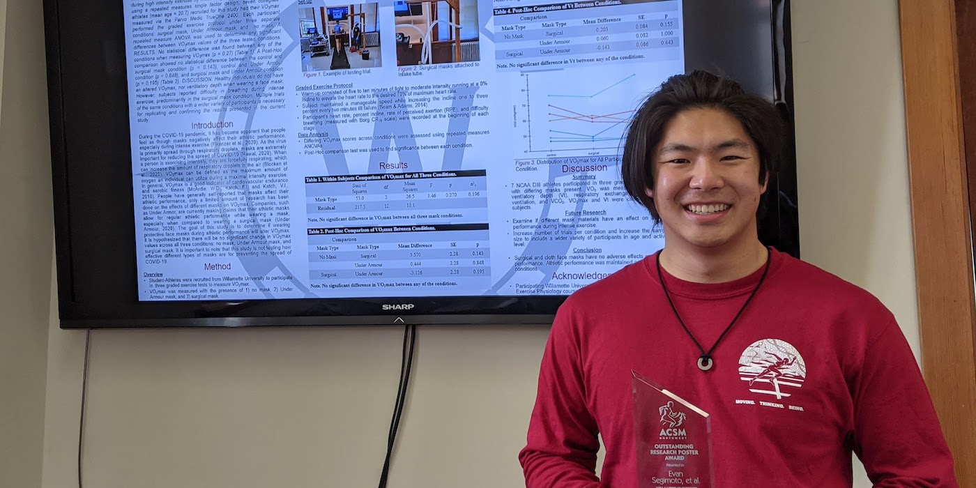 Evan Segimoto holding his award trophy in front of his winning poster