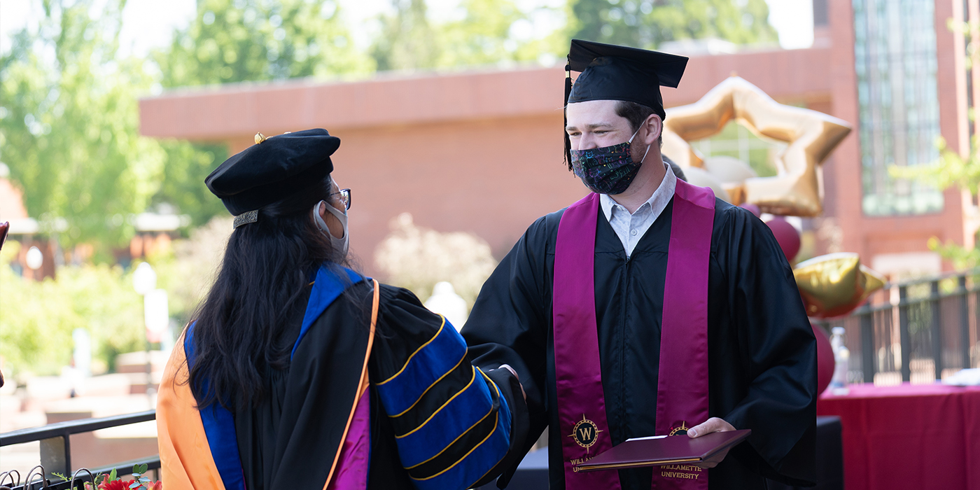 student shakes hands with a faculty member