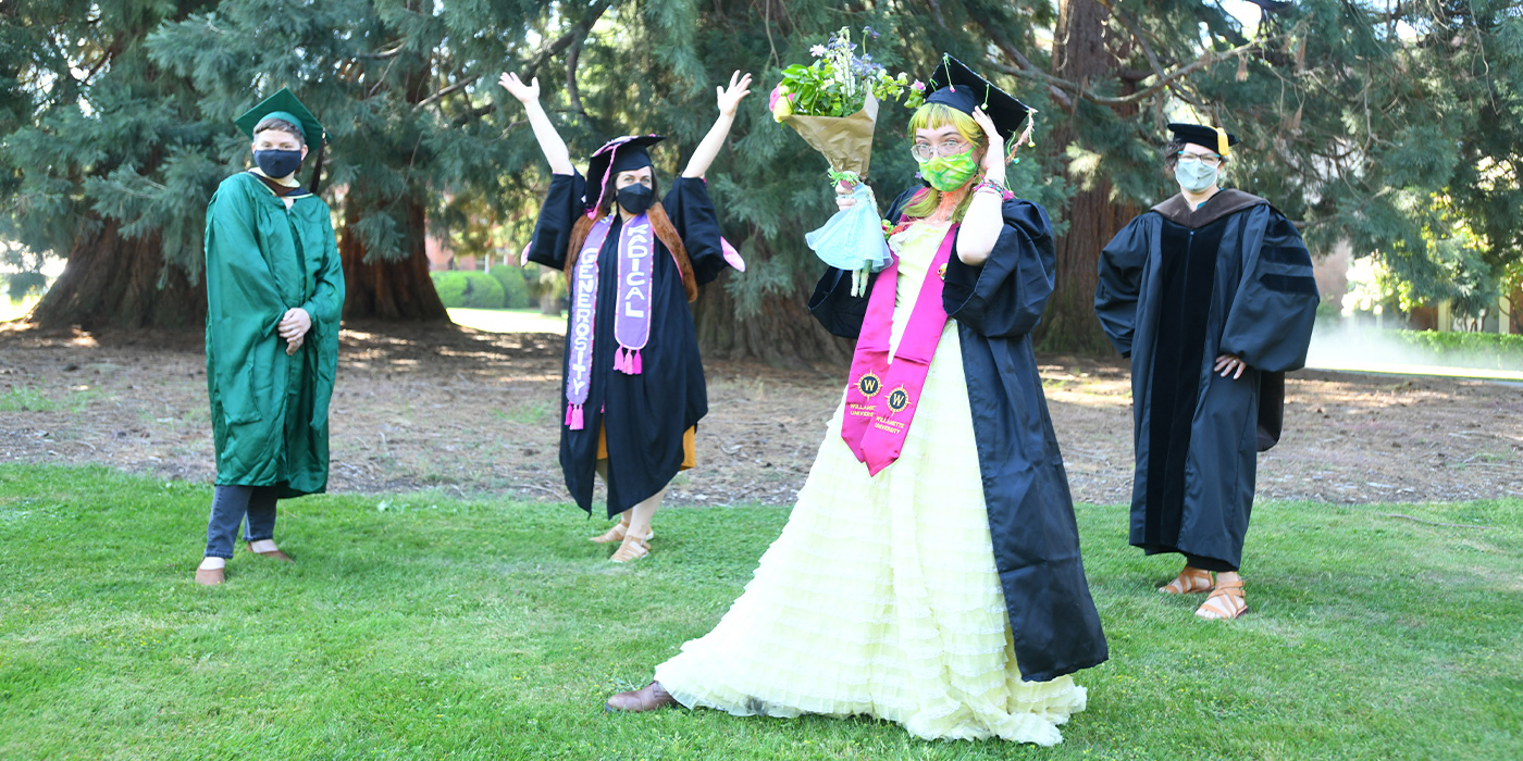 a student celebrates in front of the Star Trees with the Studio Art faculty