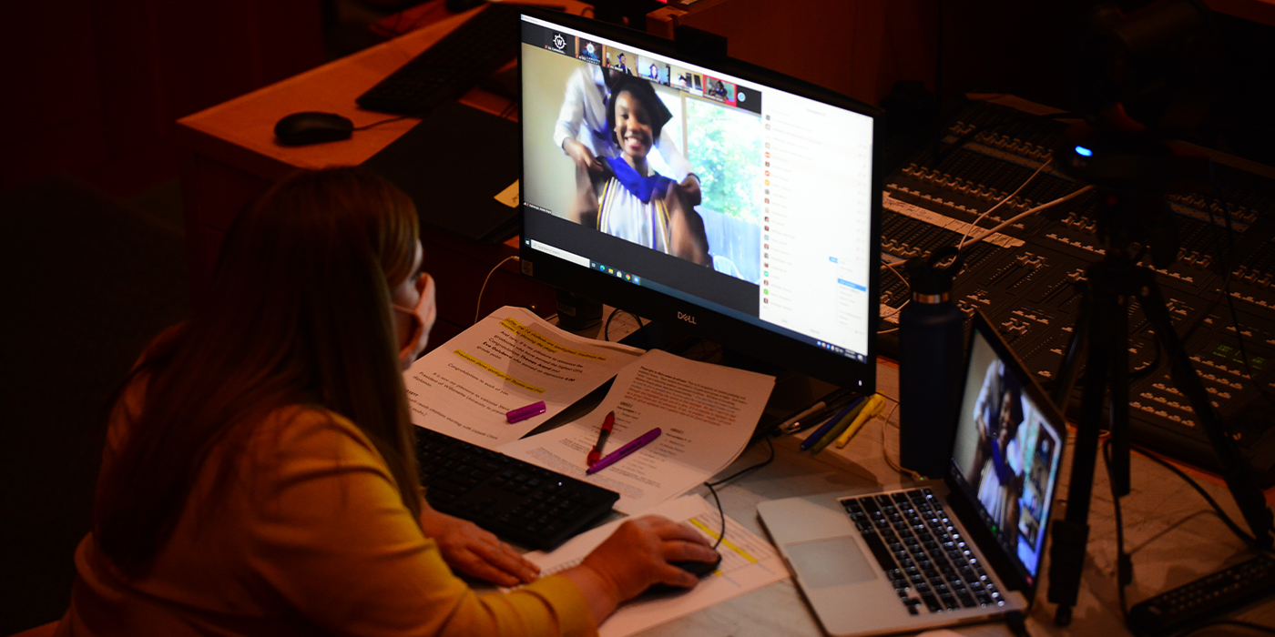 A person works at a computer screen on which a graduate is getting hooded