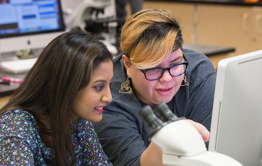 Rosa Leon Zayas and a student look intently at a computer screen