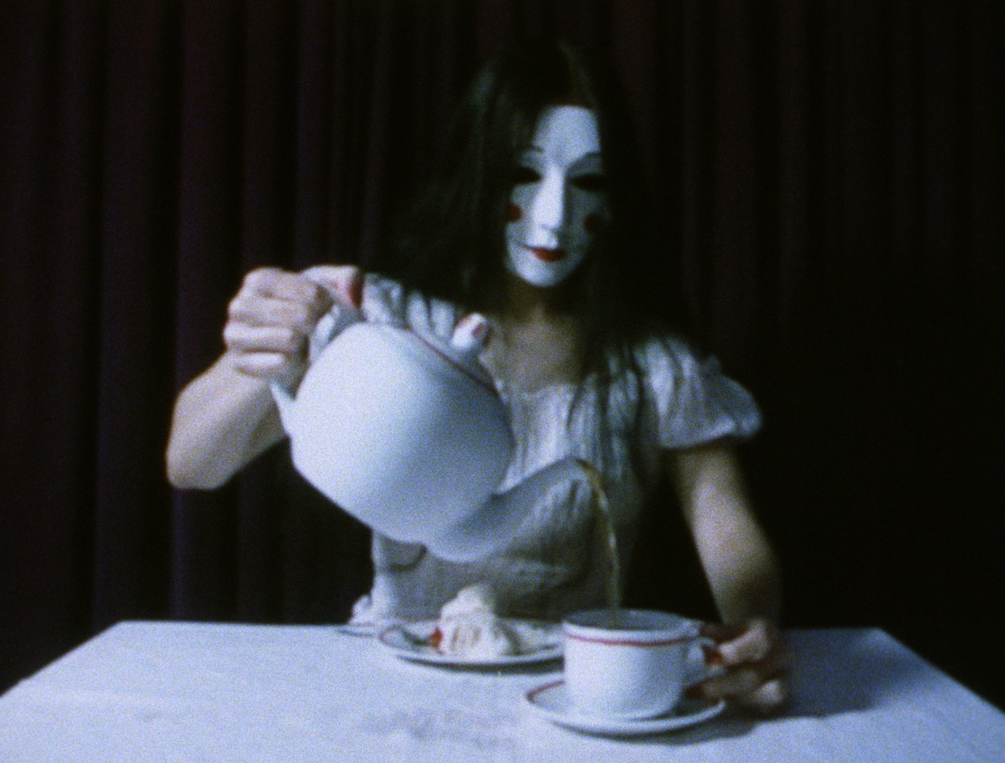 A masked woman pouring from a teapot