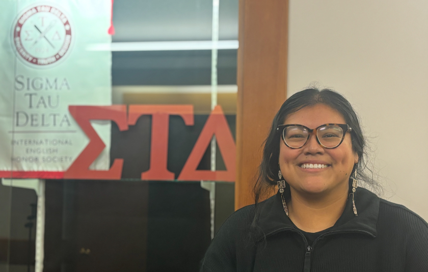 Teresa Hernandez posing with Sigma Tau Delta sign