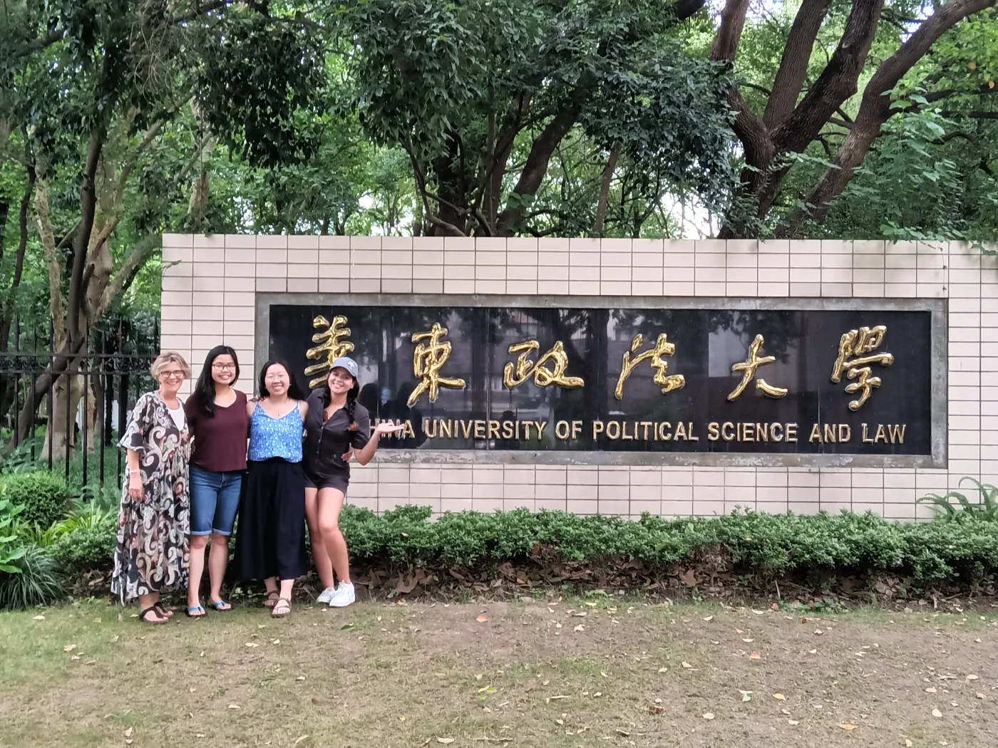 Students and a professor standing near a university sign in China.