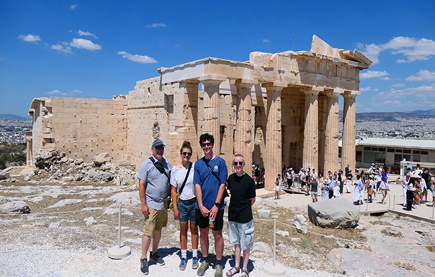 4 people standing in front of Greek ruins