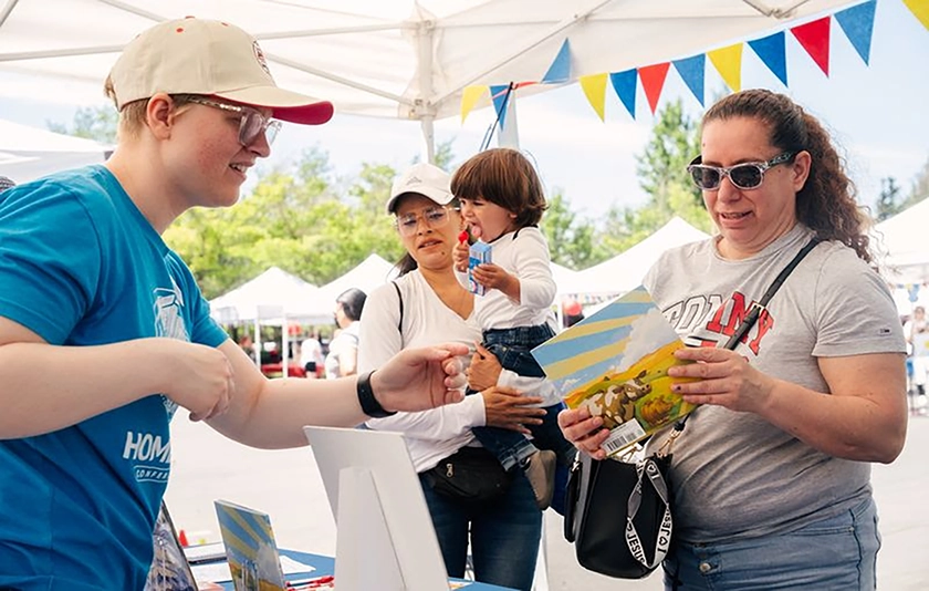 People standing under a tent looking at a book 